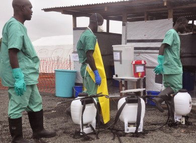 Health workers prepare disinfectant in containers, foreground, to spray at an Ebola treatment center in the city of Monrovia, Liberia.