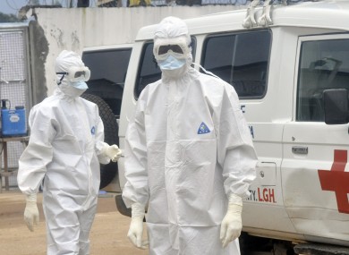 Health workers wearing protective gear wait to carry the body of a person suspected to have died from Ebola, in Monrovia, Liberia.