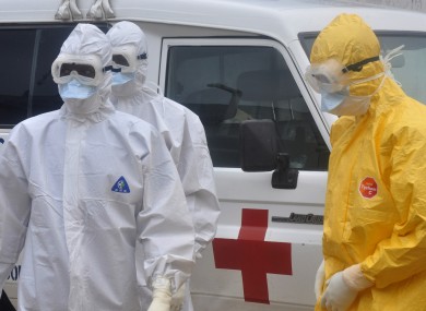 Health workers in protective gear wait to carry a body of a person suspected to have died from Ebola in Liberia.