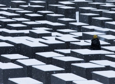 A woman visits the snow-covered Holocaust Memorial in Berlin