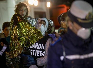 A migrant is helped disembark in the Sicilian harbor of Pozzallo, Italy, this morning.