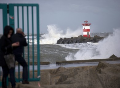 People take pictures of the waves ceasing into a storm barrier and a lighthouse during stormy weather at the entrance to the port of Scheveningen, near The Hague, Netherlands.