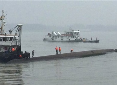 Rescue workers stand on the capsized ship.
