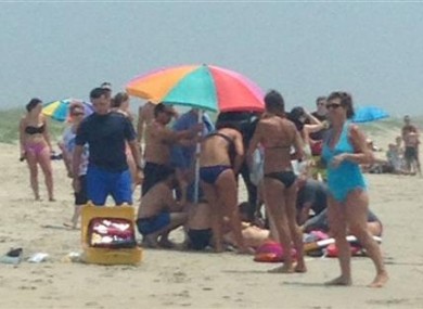 People surround and attend to a 68-year-old man that was bit by a shark in waist-deep water off Ocracoke Island, North Carolina.