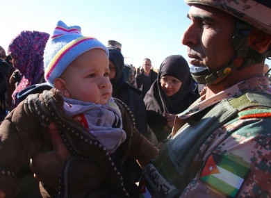 File photo of a Jordanian soldier carries a Syrian refugee child after his entry into Jordanian territory.