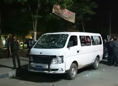 Egyptian police and civilians gather around the bullet-ridden minibus.