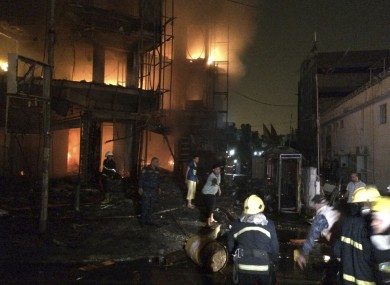 Iraqi firefighters extinguish a fire as civilians gather after a car bomb went off in Baghdad.