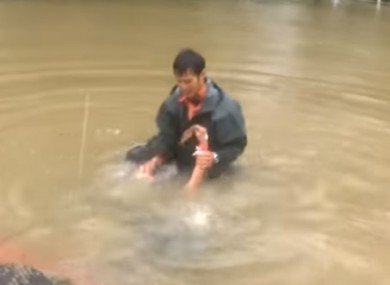 Woman being pulled from car in flood waters.