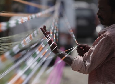 A man prepares threads with the three colors of the Indian flag for flying kites on India's Independence Day.