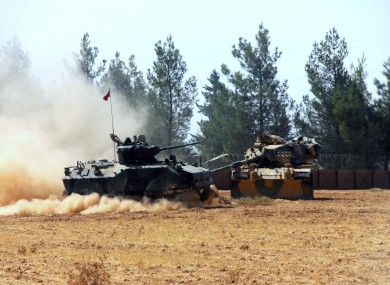 A Turkish army tank and an armored vehicle stationed near the border with Syria
