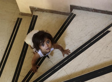 A child crawls on the steps of an abandoned hospital wing, used as a makeshift shelter for around 150 Syrian refugees, in Athens.