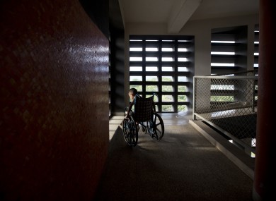 In this September 2016 photo, Marvin Osuna sits near a sunlit window in a passageway at University Hospital, in Caracas, Venezuela.