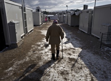 An elderly Syrian refugee man walks back to his shelter on a frozen ground at the refugee camp of Ritsona about 86 kilometers north of Athens.