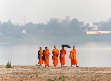 Buddhist monks walk on the Mekong river's bank in Vientiane, Laos (2012).