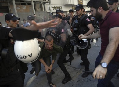 Riot police detain a person as they attempt to disperse activists