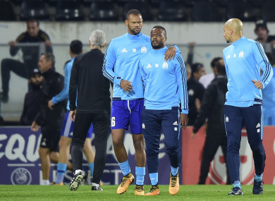 Marseille's Patrice Evra, centre right, is led away by his teammate Rolando after an altercation with Marseille supporters who trespassed into the field.