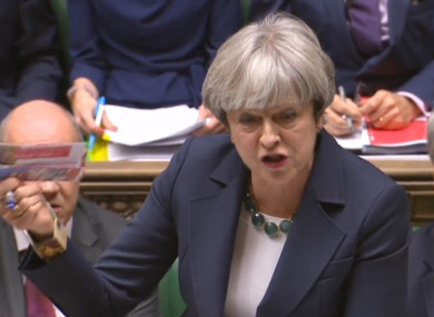 Theresa May holds up a Labour Party leaflet in the Commons during PMQs.