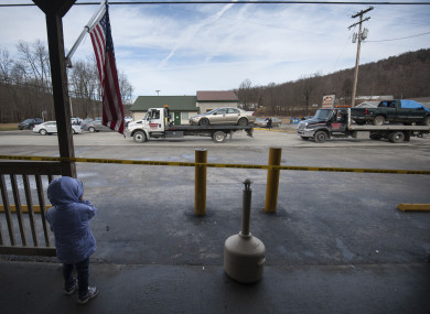 A little girl watches from the front of G&D Market as trucks remove three vehicles from the scene.
