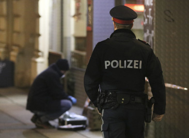 A police officer passes by a forensic expert after several people have been injured in a knife attack on the streets of Vienna