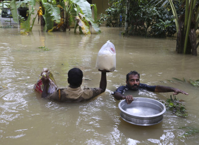An Indian policeman, left, and a volunteer carry essential supplies for stranded people in a flooded area in Chengannur.