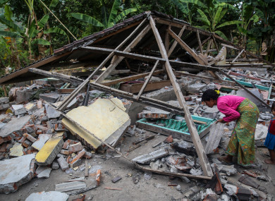 A woman search her belongings at ruins of her houses after an earthquake hit on Sunday in North Lombok, Indonesia on Wednesday, 8 August