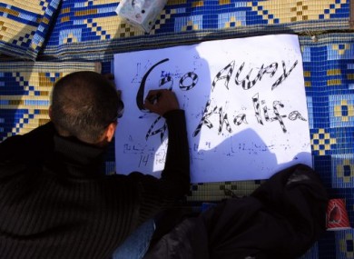 A Bahraini anti-government protester prepares a sign at a makeshift camp at the Pearl roundabout in Manama, Bahrain, today.