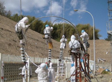 Workers wearing protective suits work to restore electricity at the Fukushima nuclear power plant.