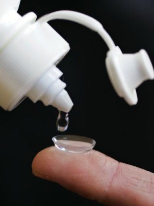 A drop of Bausch & Lomb eye care product is poured onto a contact lens.