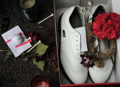 Candles and a red flower are seen beside golf shoes outside the church in Pedrena earlier.