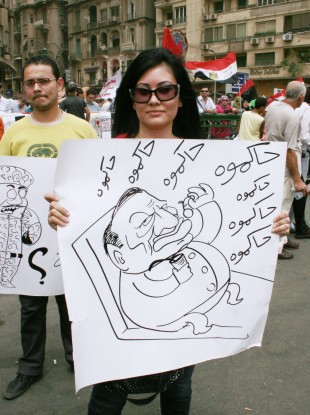 A woman holds a poster illustrating former Egyptian President Hosni Mubarak during a pro-democracy demonstration at Tahrir Square on Friday.