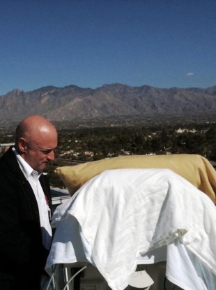 Mark Kelly, stands with his wife Gabrielle Giffords as she looks from her bed at the Santa Catalina Mountains while on an outdoor deck at University Medical Center in Tucson, Arizona in January.