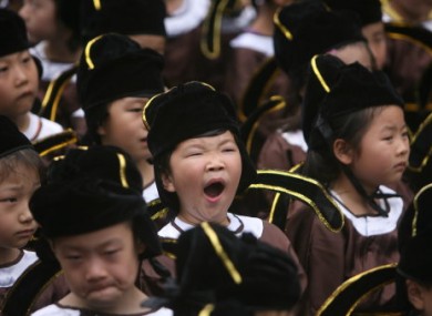 Pupils in traditional costume photographed during a school enrolment ceremony in Nanjing, China, today.