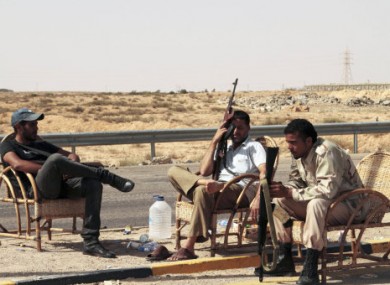 Revolutionary fighters sit at a checkpoint outside Sirte, Libya, today.