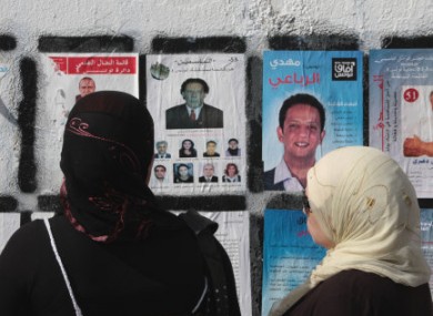Tunisians women read election wall posters in Tunis on Saturday.