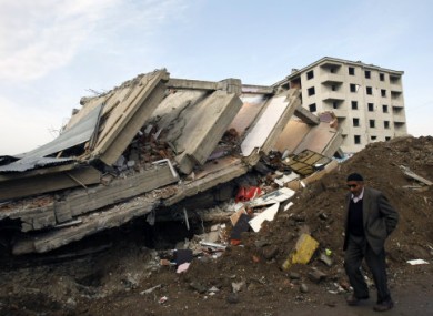A man walks by a collapsed building in Ercis, eastern Turkey, yesterday.