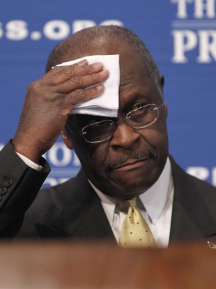 Herman Cain wipes his forehead before answering questions at the National Press Club in Washington yesterday.