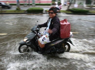 A Bangkok resident rides through rising floodwater in the capital on Friday.