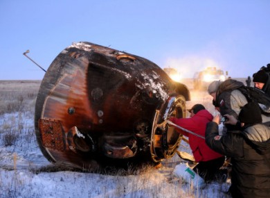 Onlookers check the Soyuz spacecraft after the three astronauts emerged today.