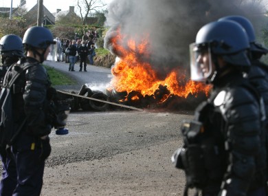 Police face protesters over a burning barricade in Normandy, France today.
