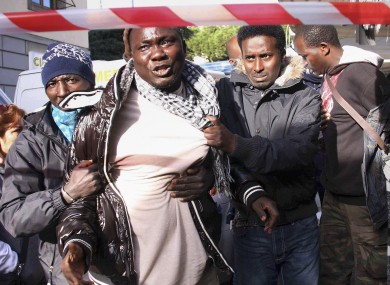 Senegalese immigrants cry as they view the scene of the racist attack