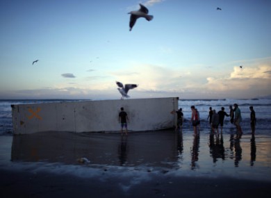 October 2011: People on Mount Maunganui beach study one of the containers washed up from the Rena.