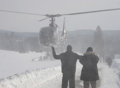 Bosnian people wave to a helicopter as they await food supplies after being cut off by the snow.