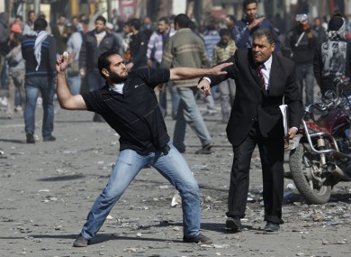 A man urges a protester to stop throwing stones at security forces during today's clashes in Cairo.