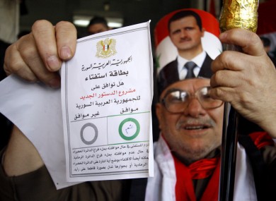A Syrian man holds up his ballot paper at a polling station during a referendum on the new constitution in Damascus yesterday. The EU's foreign ministers today introduced new asset embargoes against Syria.