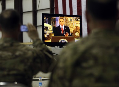 Military personnel watch on a screen as President Barack Obama makes a live address at Bagram Air Base