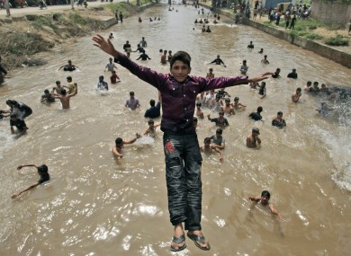A young boy jumps into the water as he and his friends escape the heat in a canal, Lahore, Pakistan.