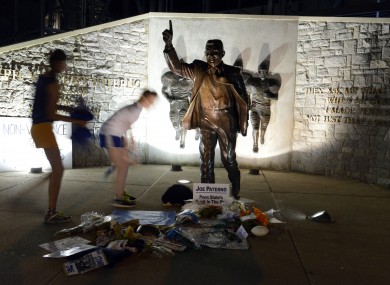 People visit the Joe Paterno statue before its removal from the Penn State campus on Sunday morning.