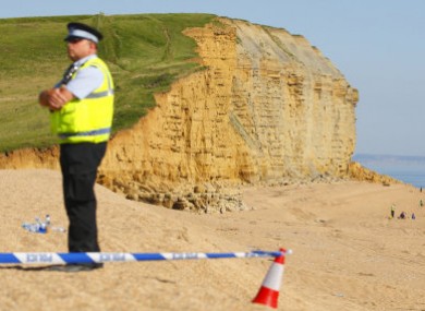 A policeman stands watch as rescuers work at the scene of yesterday's landslide in Dorset.