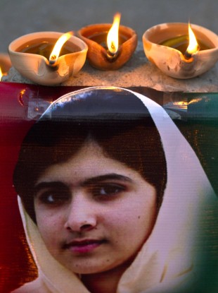 Clay lamps burn near a poster of 15-year-old Malala Yousufzai in Islamabad.
