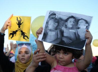 Syrian protesters carry a placards showing dead Syrian children, during a protest in front of the Syrian embassy in Jordan.